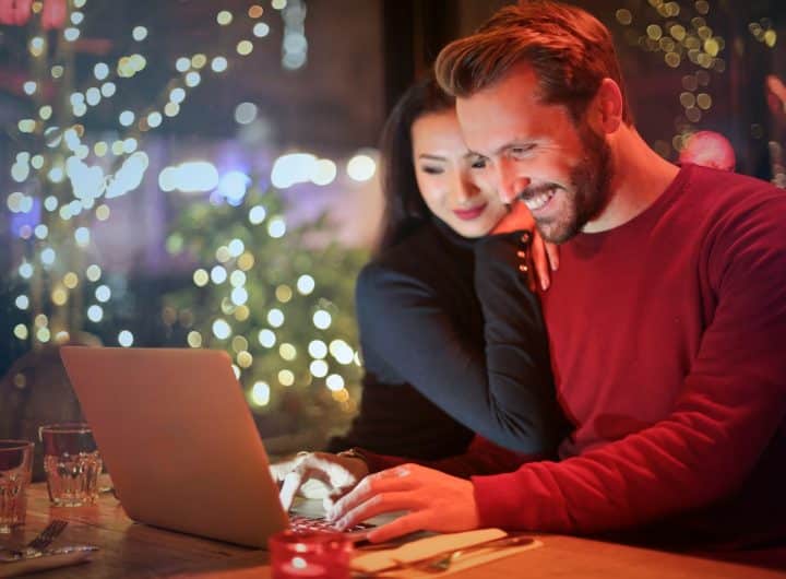 man and woman looking on silver laptop while smiling